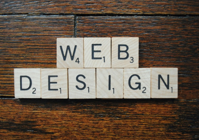 Scrabble-Buchstaben auf Holzuntergrund buchstabieren "WEB DESIGN".